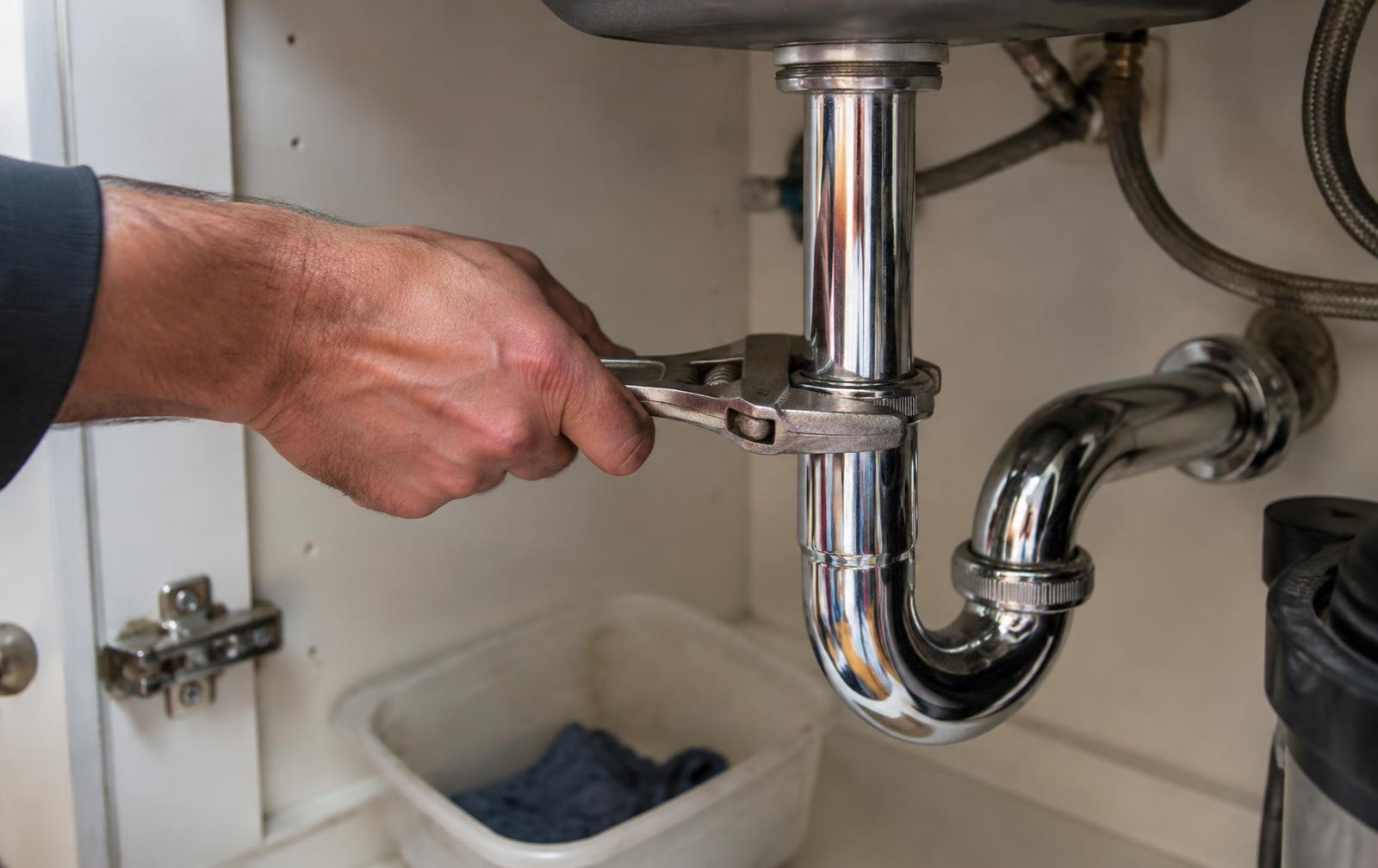Professional plumber repairing pipes under a residential sink